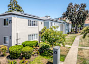 Thumbnail 10 of 11 - A residential building with a grey facade and a green lawn in front.