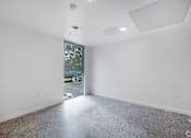 Thumbnail 16 of 28 - A large empty room with a doorway leading to a balcony.