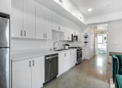 Thumbnail 15 of 28 - A modern kitchen with white cabinets and a green couch.