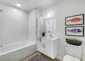 Thumbnail 13 of 28 - A white bathroom with a white tub, sink, and toilet.