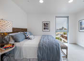 Thumbnail 9 of 28 - A bedroom with a large bed and a view of the outside.