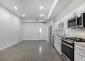 Thumbnail 6 of 28 - A kitchen with white cabinets and stainless steel appliances.