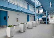 Thumbnail 3 of 6 - A hallway with blue doors and white planters.