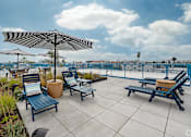 Thumbnail 28 of 28 - A patio with blue chairs and a striped umbrella.