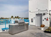 Thumbnail 4 of 6 - A white building with a blue fence and a grill in front of it.