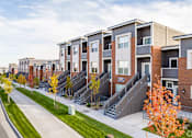 Thumbnail 5 of 8 - a row of townhomes with stairs and grass and trees