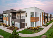 Thumbnail 3 of 22 - A modern apartment complex with a landscaped courtyard in front.