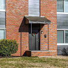 A red brick building with a black door and a small porch. at Blacklark Apartments, Apartments, Kansas City, KS
