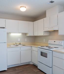 A white kitchen with a refrigerator, stove, and cabinets.