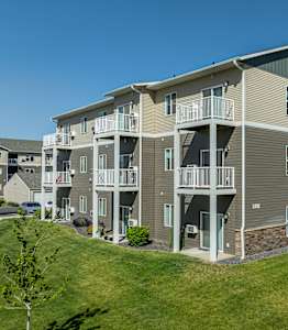 an exterior view of an apartment building with a green lawn