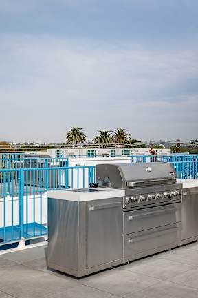 A white building with a blue fence and a grill in front of it.
