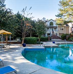 A pool with a yellow umbrella and blue loungers.