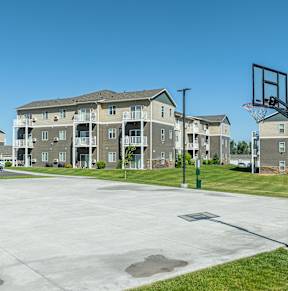 an empty basketball court with an apartment building in the background