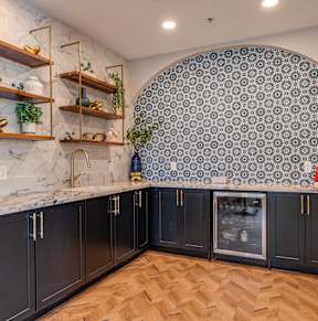 A kitchen with black cabinets and a marble countertop.