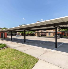 Sugar Mill Apartments in Addis, LA photo of a covered parking lot with a building in the background