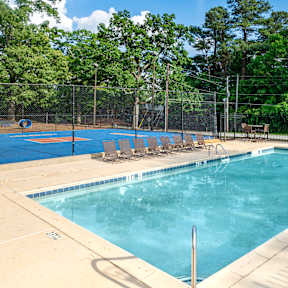 A large outdoor swimming pool surrounded by trees and a fence.