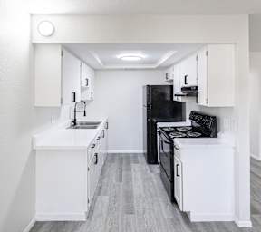 A kitchen with black appliances and white cabinets.
