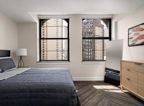A bedroom with a large bed and a window overlooking a cityscape.