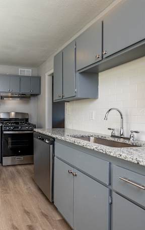 A kitchen with a black refrigerator and a stainless steel dishwasher. at Blacklark Apartments, Apartments, Kansas City, KS