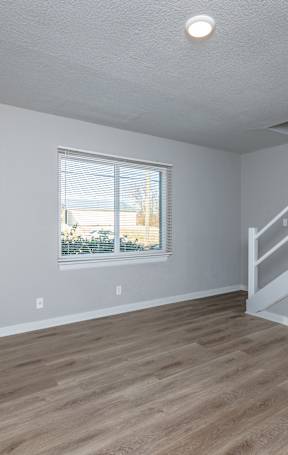 A room with wooden flooring and a window with blinds. at Blacklark Apartments, Apartments, Kansas City, KS