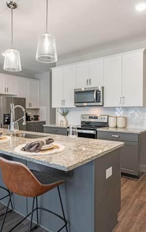 a kitchen with white cabinets and a marble counter top