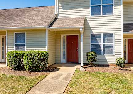 A two-story house with a red door and a brown roof.