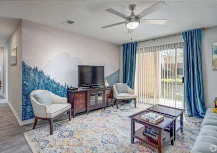 A living room with a television, two chairs, a coffee table, and a rug.