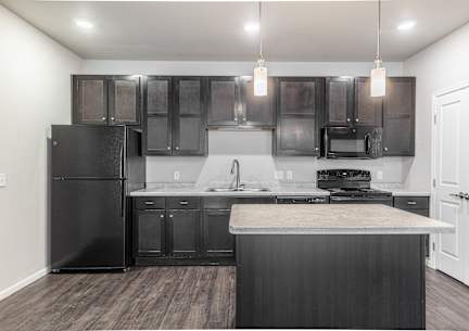 an empty kitchen with black appliances and dark wood cabinets
