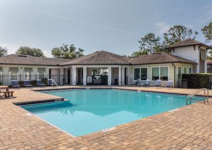 A swimming pool surrounded by a brick patio and a gazebo.