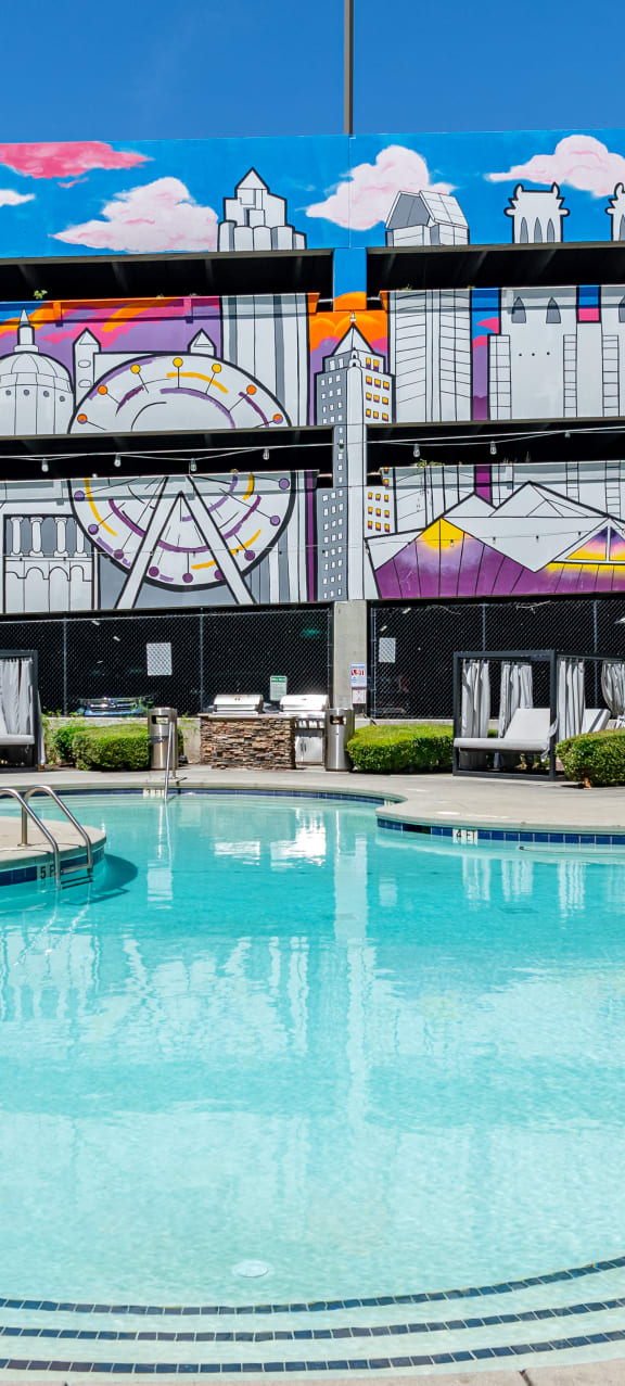 a swimming pool in front of a building with a mural on it