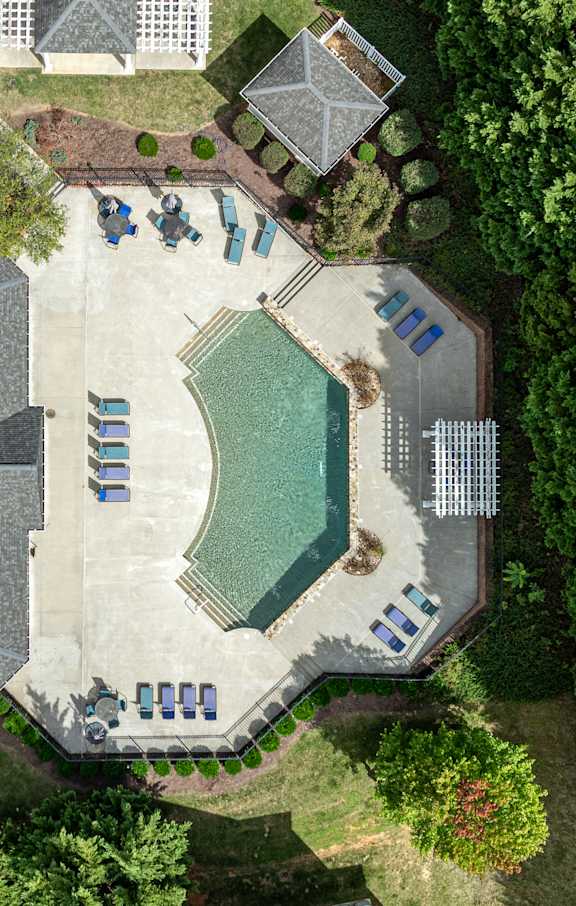 A bird's eye view of a residential area with a swimming pool and a parking lot.