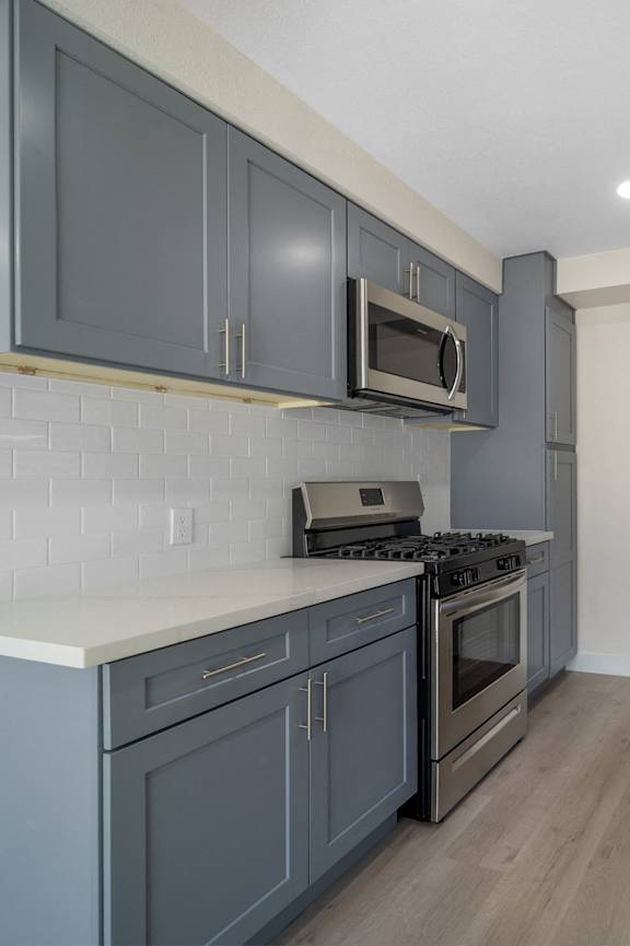 A modern kitchen with white cabinets and stainless steel appliances. at Hamilton Courtyard Apartments, Costa Mesa, CA, 92627