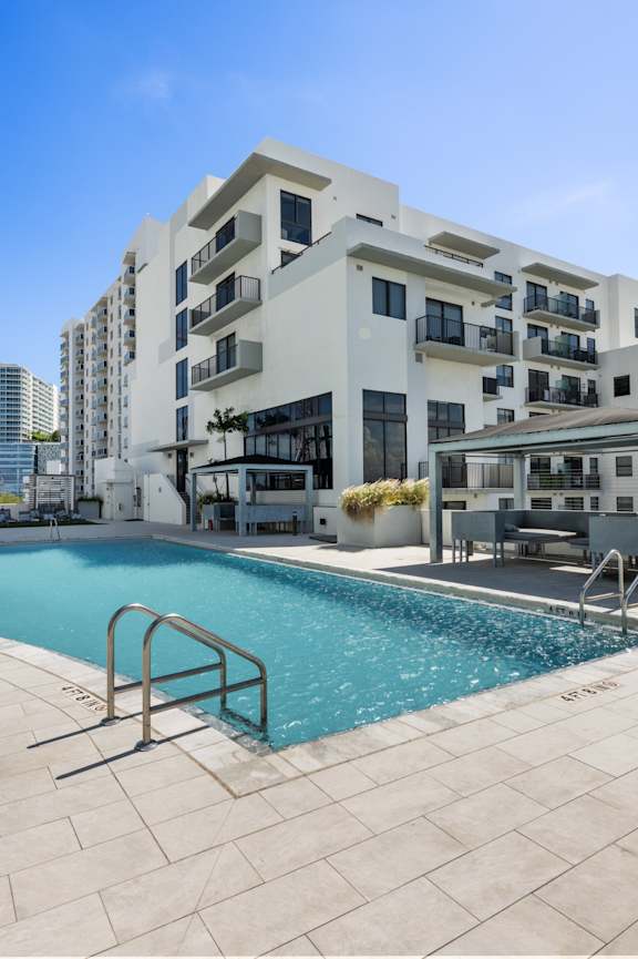 a swimming pool with orange chairs and a building in the background