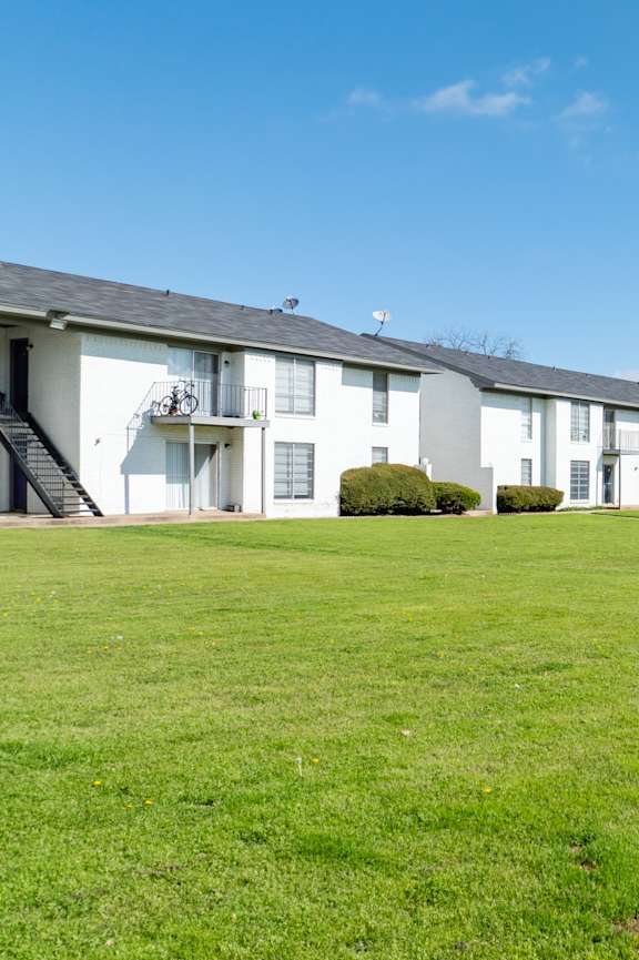 A row of white houses with green lawns in front.