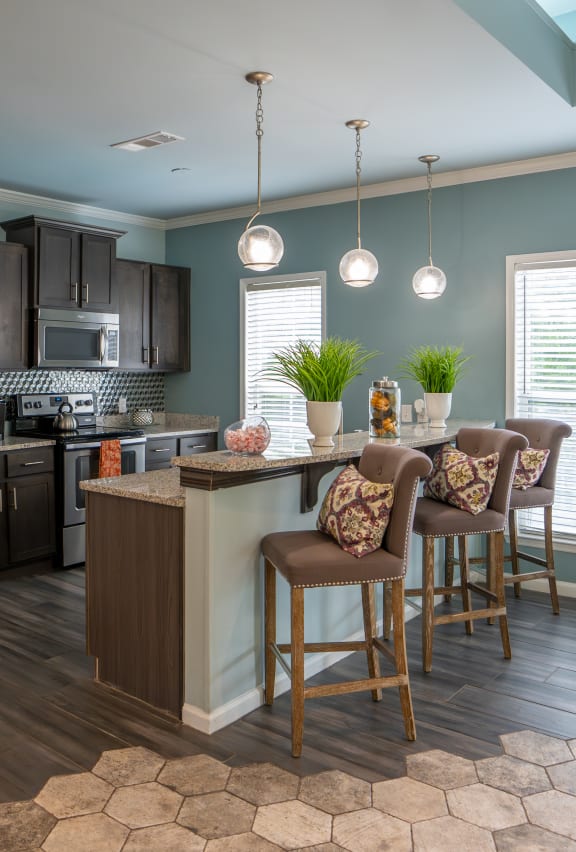 a kitchen with stainless steel appliances and a bar with chairs