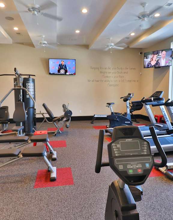 a gym with exercise equipment and a tv on the wall