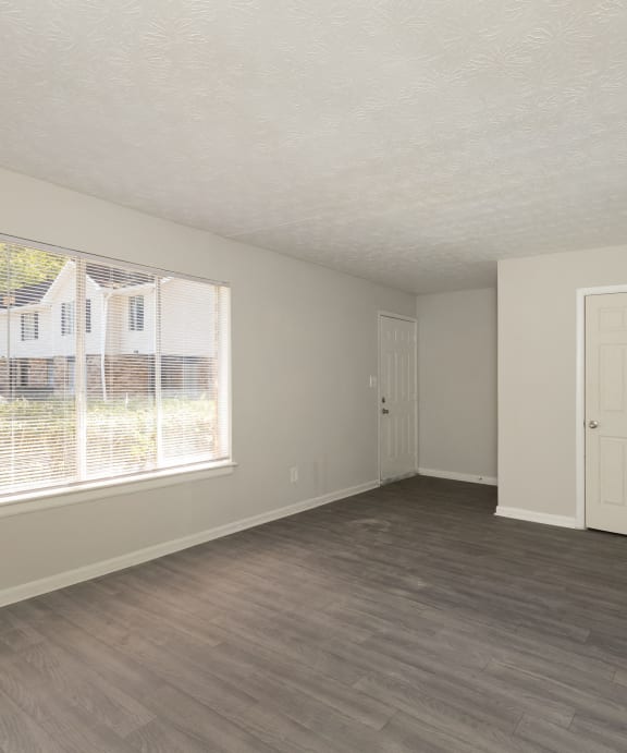 an empty living room with a large window and wooden floors at Hidden Woods, Decatur, Georgia