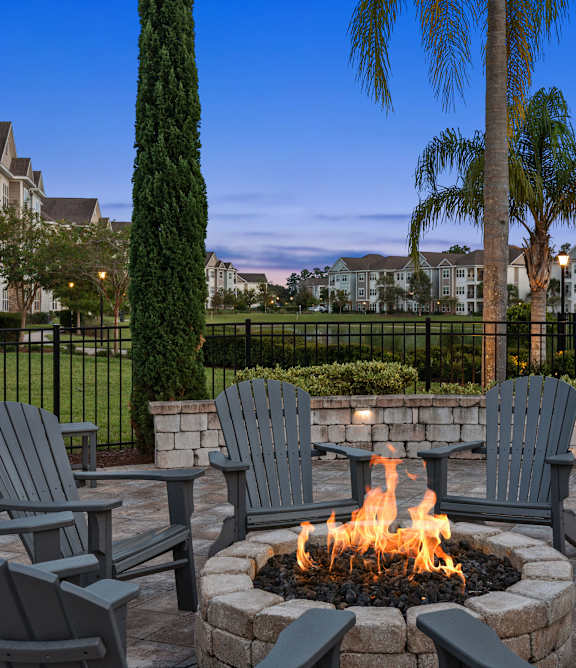 A fire pit with a fire burning surrounded by chairs.