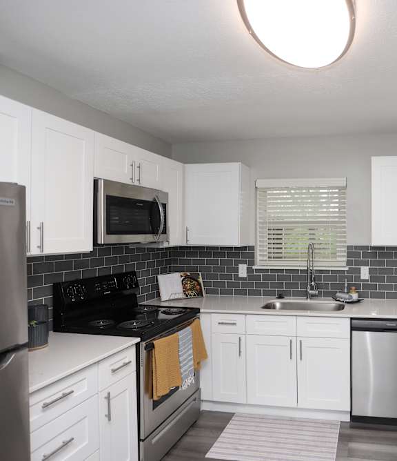 A kitchen with white cabinets and a black stove top.at Spinnaker Court, Indianapolis