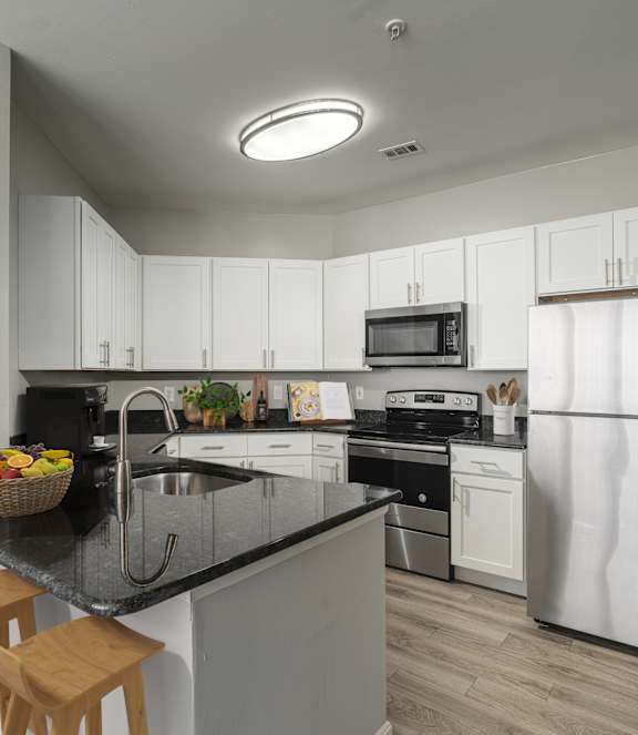 A kitchen with white cabinets and a black countertop.