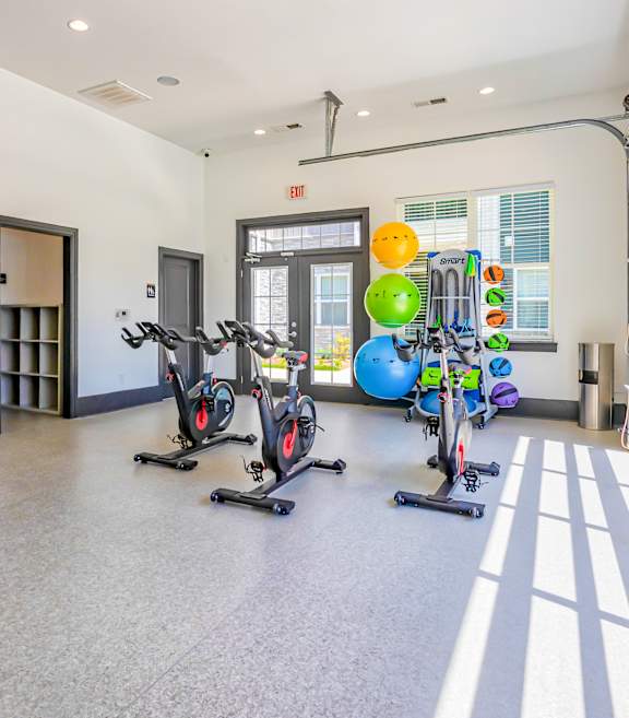 A gym with exercise equipment and a large mirror on the wall.