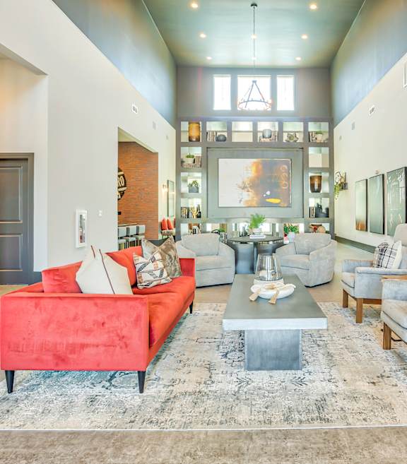 A living room with a red couch and a grey rug.