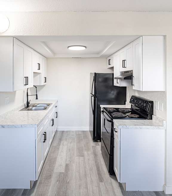 A kitchen with black appliances and white cabinets.