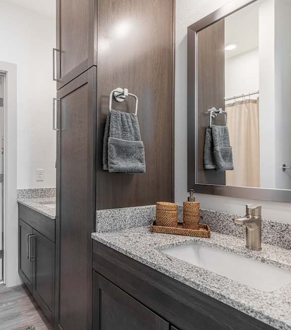 A bathroom with a sink, mirror, and a shower with a door open.