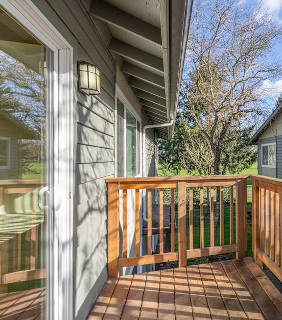 A wooden deck with a railing and a house in the background.