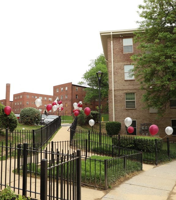 a black wrought iron fence with red and white balloons in front of a brick building