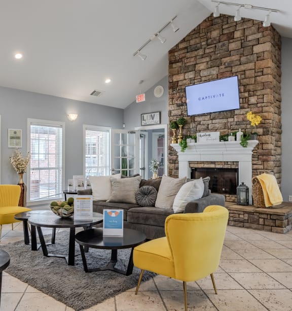 a living room with yellow chairs and a brick fireplace at Greens at Stonecreek, Lithonia, GA, 30038