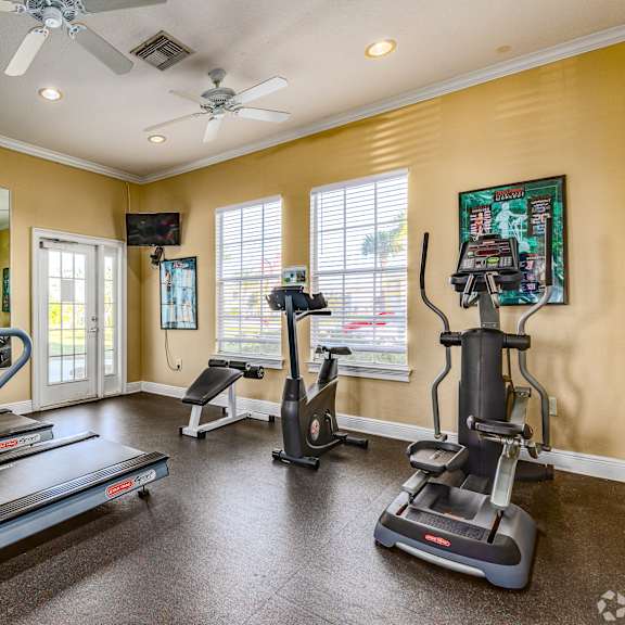 A spacious home gym with treadmills, elliptical machines, and a fan.