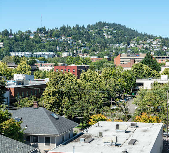 A cityscape with buildings and trees under a clear sky.
