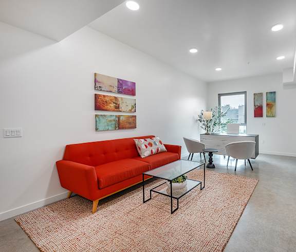 A red couch sits in a living room with a glass table and chairs.
